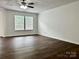 Spacious living area with wood-look flooring, neutral walls, ceiling fan, and a large window for natural light at 12713 Frank Wiley Ln, Charlotte, NC 28278