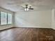 Bright living room featuring wood-look floors, neutral walls, a ceiling fan, and a large window for natural light at 12713 Frank Wiley Ln, Charlotte, NC 28278