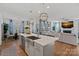 Open-concept kitchen with stainless steel appliances, an island with bar seating, and an adjacent living room at 14004 Fiery Mist Way, Huntersville, NC 28078