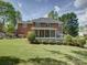 Spacious backyard showcasing a well-manicured lawn, mature trees, and a charming brick home with a screened porch at 15824 Feeny Ct, Charlotte, NC 28278