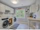 Well-lit laundry room with modern washer and dryer, ample cabinet space, and unique decor at 15824 Feeny Ct, Charlotte, NC 28278