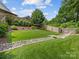 Lush backyard featuring a rock-lined stream, manicured lawn, and privacy fencing at 1614 Brook Rd, Charlotte, NC 28205