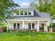 Charming home featuring a manicured lawn, a light gray roof, white trim and a welcoming front porch at 1614 Brook Rd, Charlotte, NC 28205
