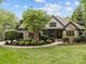Beautiful stone home with a well-manicured lawn and lush landscaping showcasing its curb appeal at 21305 Sandy Cove Rd, Cornelius, NC 28031
