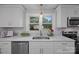 Close-up of kitchen sink area featuring quartz countertops, white cabinets, and view of backyard at 322 Corriher Heights Ave, China Grove, NC 28023