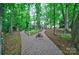 Beautiful landscaped yard with brick walkway leading to charming home through lush greenery and trees at 3400 Baucom Manor Rd, Monroe, NC 28110