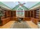 Home office featuring custom wood built-ins, hardwood floors, a vaulted ceiling, and large arched window at 3400 Baucom Manor Rd, Monroe, NC 28110