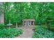 Quaint outdoor shed with charming details, set amidst lush foliage and a stone pathway at 3400 Baucom Manor Rd, Monroe, NC 28110