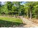 Landscaped backyard with a stone pathway leading to a relaxing seating area in a wooded setting at 4563 Osprey Run Ct, Denver, NC 28037