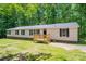 Exterior view of home with wood porch, black shutters, and tree-lined backyard at 5376 Walter Estate Ln, Iron Station, NC 28080