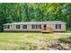 Inviting home with wood porch and lush green yard surrounded by dense forest at 5376 Walter Estate Ln, Iron Station, NC 28080