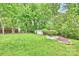 Lush backyard with mature trees, a manicured lawn, a storage shed, and decorative pond at 611 Heathermoor Ct, Charlotte, NC 28209