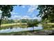 Picturesque lake view surrounded by green trees, reflecting a beautiful sky with scattered clouds at 611 Heathermoor Ct, Charlotte, NC 28209