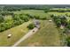 Scenic aerial view of a brick home on lush acreage, complemented by a lengthy gravel driveway and verdant trees at 6218 Indian Trail Fairview Rd, Indian Trail, NC 28079