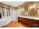 A bathroom featuring a bathtub, glass shower, dual mirrors, and a wood vanity at 6218 Indian Trail Fairview Rd, Indian Trail, NC 28079