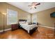 A cozy bedroom featuring hardwood floors, a ceiling fan, and natural light from two windows at 6218 Indian Trail Fairview Rd, Indian Trail, NC 28079