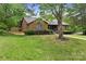Charming brick home featuring mature trees, manicured lawn, and welcoming front entrance at 7221 Leaves Ln, Charlotte, NC 28213