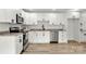 Well-lit kitchen with white cabinets, stainless steel appliances, and light wood floors at 7221 Leaves Ln, Charlotte, NC 28213