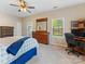 Bright bedroom boasts a ceiling fan, a computer desk, a window overlooking trees and a large dresser at 7325 Forrest Rader Dr, Mint Hill, NC 28227