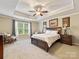 Spacious main bedroom boasts tray ceiling, ceiling fan, neutral carpet, and a large window at 7325 Forrest Rader Dr, Mint Hill, NC 28227