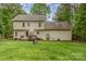 Rear view of the home displaying its siding, large backyard, open deck with umbrella, and a fire pit area at 7525 Windy Pine Cir, Denver, NC 28037