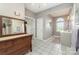 Bright bathroom with double sink vanity, decorative mirror, arched window with natural light, and ceramic tile flooring at 7525 Windy Pine Cir, Denver, NC 28037