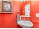 Bright bathroom with an orange accent wall, a decorative painting, and a white pedestal sink at 7525 Windy Pine Cir, Denver, NC 28037