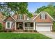 Charming two-story brick home featuring a welcoming front porch with white columns and manicured landscaping at 7811 Compton Ct, Charlotte, NC 28270