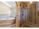 Bathroom features a glass shower, soaking tub, vanity, beautiful tiling, and lots of natural light at 11917 Chevis Ct, Charlotte, NC 28277