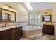 Elegant bathroom features a soaking tub, double vanities, mirrors, skylight, and plenty of natural light at 11917 Chevis Ct, Charlotte, NC 28277