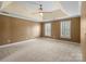 Spacious bedroom with neutral carpet, tray ceiling, crown molding, and natural light from large windows at 11917 Chevis Ct, Charlotte, NC 28277