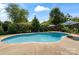 Inviting in-ground pool with a stone border, surrounded by lush landscaping and striped umbrellas at 11917 Chevis Ct, Charlotte, NC 28277