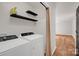 Well-equipped laundry room with washer, dryer, shelving, and wood floors at 177 Candlestick Dr, Statesville, NC 28625