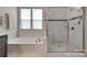Inviting bathroom with tub, glass shower, and natural light from window at 4211 Maggie Springs Way, Clover, SC 29710