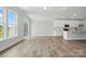 Open-concept living area with hardwood floors, leading to a modern kitchen with white cabinets at 4254 Black Ct # 231, Harrisburg, NC 28075