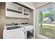 Laundry room with white washer and dryer, shelving, and a window overlooking the backyard at 6412 Old Meadow Rd # 69, Charlotte, NC 28227