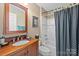 Traditional bathroom showcasing a wood vanity, patterned shower curtain, and classic fixtures at 6914 Riesman Ln # 95, Charlotte, NC 28210