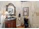 Elegant powder room with dark wood vanity, ornate mirror, unique wallpaper, and a black toilet at 6914 Riesman Ln # 95, Charlotte, NC 28210