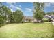 Expansive front yard with mature trees surrounds a cozy house with white trim and a covered porch, creating inviting curb appeal at 7106 Kinsmore Ln, Charlotte, NC 28269