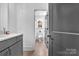 Modern bathroom with gray cabinets, quartz countertop, and a view into the toilet area with a window, showcasing a clean design at 8136 Energy Ln, Catawba, NC 28609