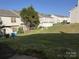Green backyard of residential home with a grassy lawn and trees in the background at 12120 Stratfield Place Cir, Pineville, NC 28134