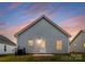 Rear view of home with white siding, white door, and manicured lawn, set against a colorful sky at 1619 Martin Ave, Gastonia, NC 28052