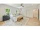 Bright bedroom features hardwood floors, large windows, ceiling fan and neutral decor with a decorative bench at the foot of the bed at 205 Coxe Ave, Charlotte, NC 28208