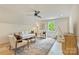 Bonus room features hardwood floors, a window, ceiling fan, and seating area with white couch and accent chairs at 205 Coxe Ave, Charlotte, NC 28208