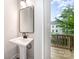 Stylish powder room with a pedestal sink, modern faucet, mirror, and open door to the outdoor balcony at 208 Mattoon St, Charlotte, NC 28216