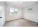 Bright bedroom with two windows and a black door, featuring light wood-style floors at 208 Mattoon St, Charlotte, NC 28216