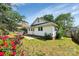 A partial view of the backyard and patio, surrounded by a partial fence, shrubbery, and greenery at 209 S Ransom St, Gastonia, NC 28052