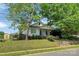 Charming single-story home with mature shade trees, a blue front door, and lush landscaping at 209 S Ransom St, Gastonia, NC 28052