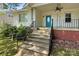 Charming covered front porch leading to a blue front door, decorative columns and railing, and brick foundation at 209 S Ransom St, Gastonia, NC 28052