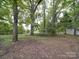 Open backyard space surrounded by large trees and featuring a small outbuilding in the background at 2721 Tara Dr, Monroe, NC 28112